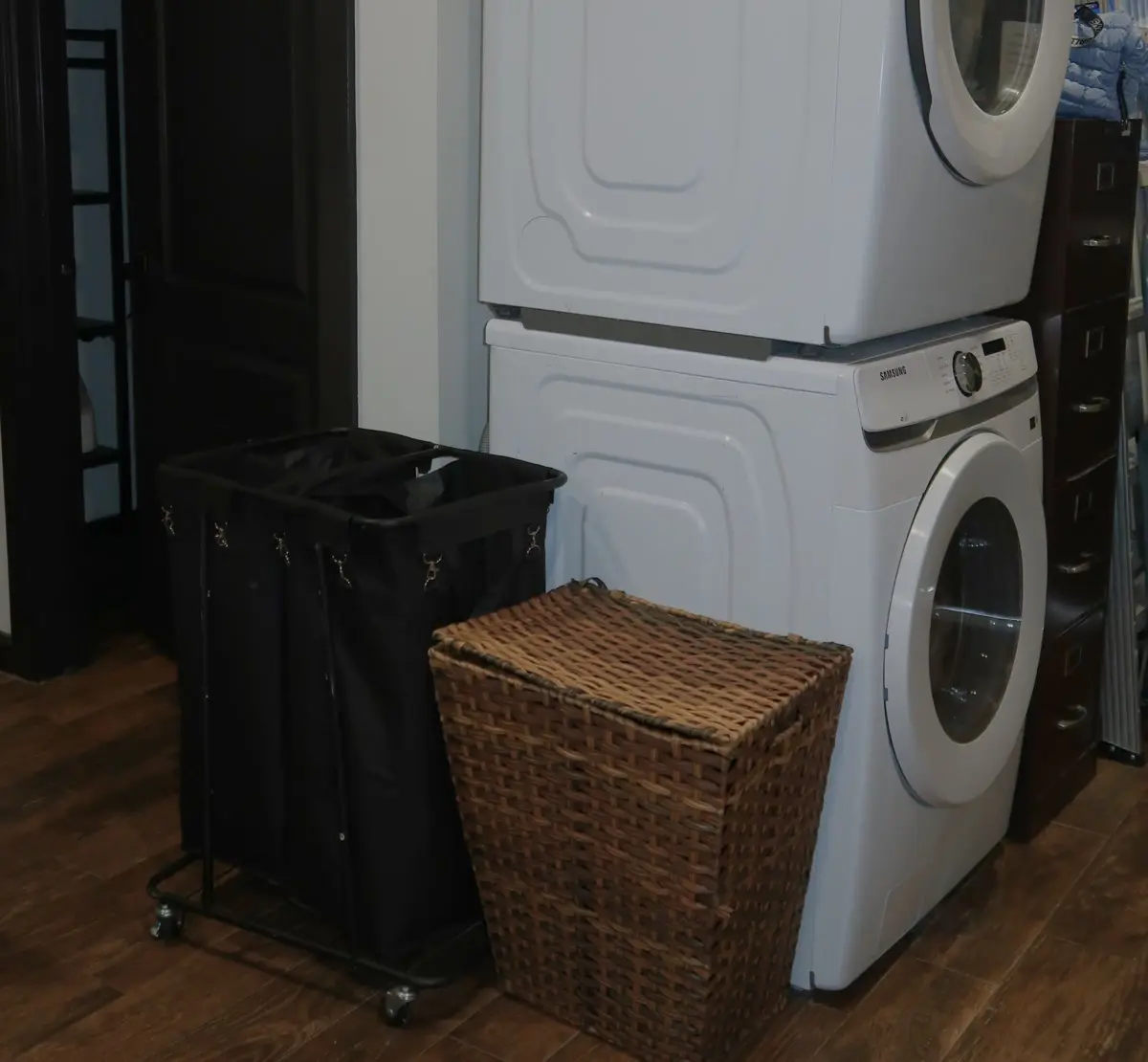 Stacked washer and dryer beside laundry baskets