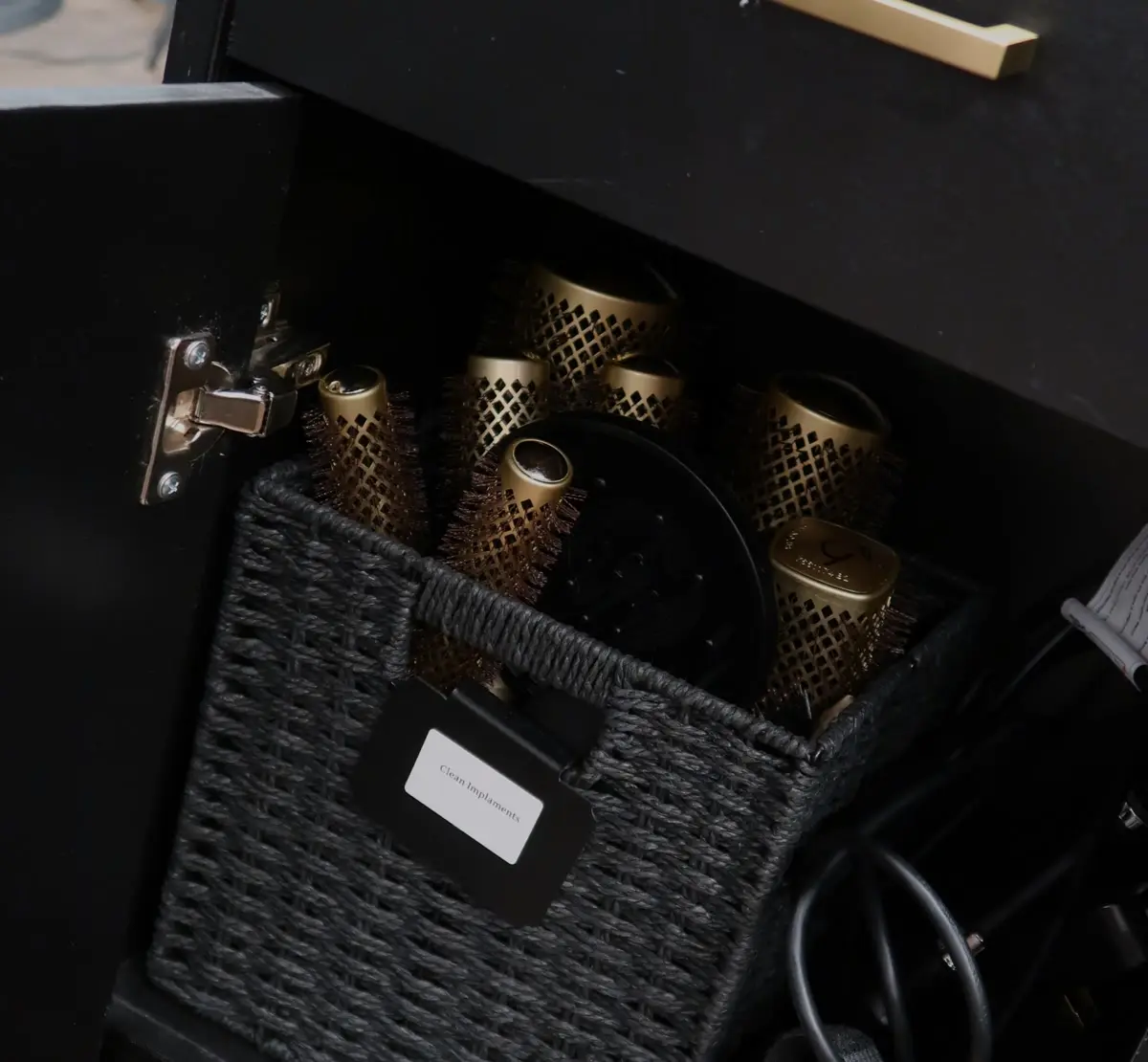 Open cabinet drawer holding gold round brushes and hot tools